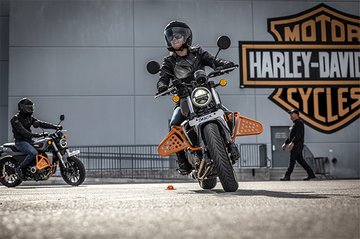 People learning to ride a motorcycle on a training range