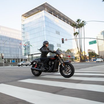 Woman riding a LiveWire motorcycle down a street.