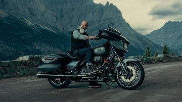 man on parked motorcycle with mountains in background